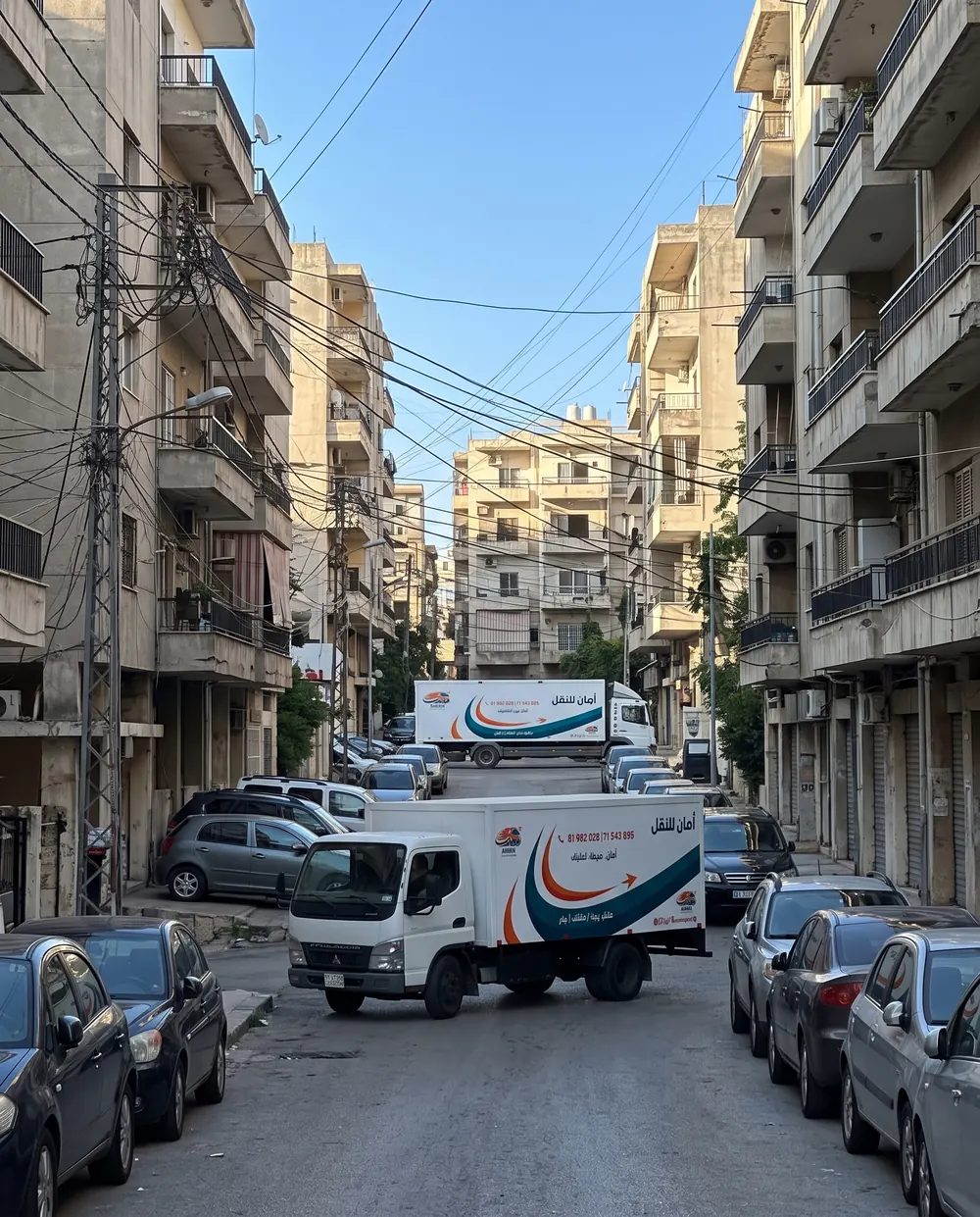 Two AMAN trucks on a narrow Beirut street